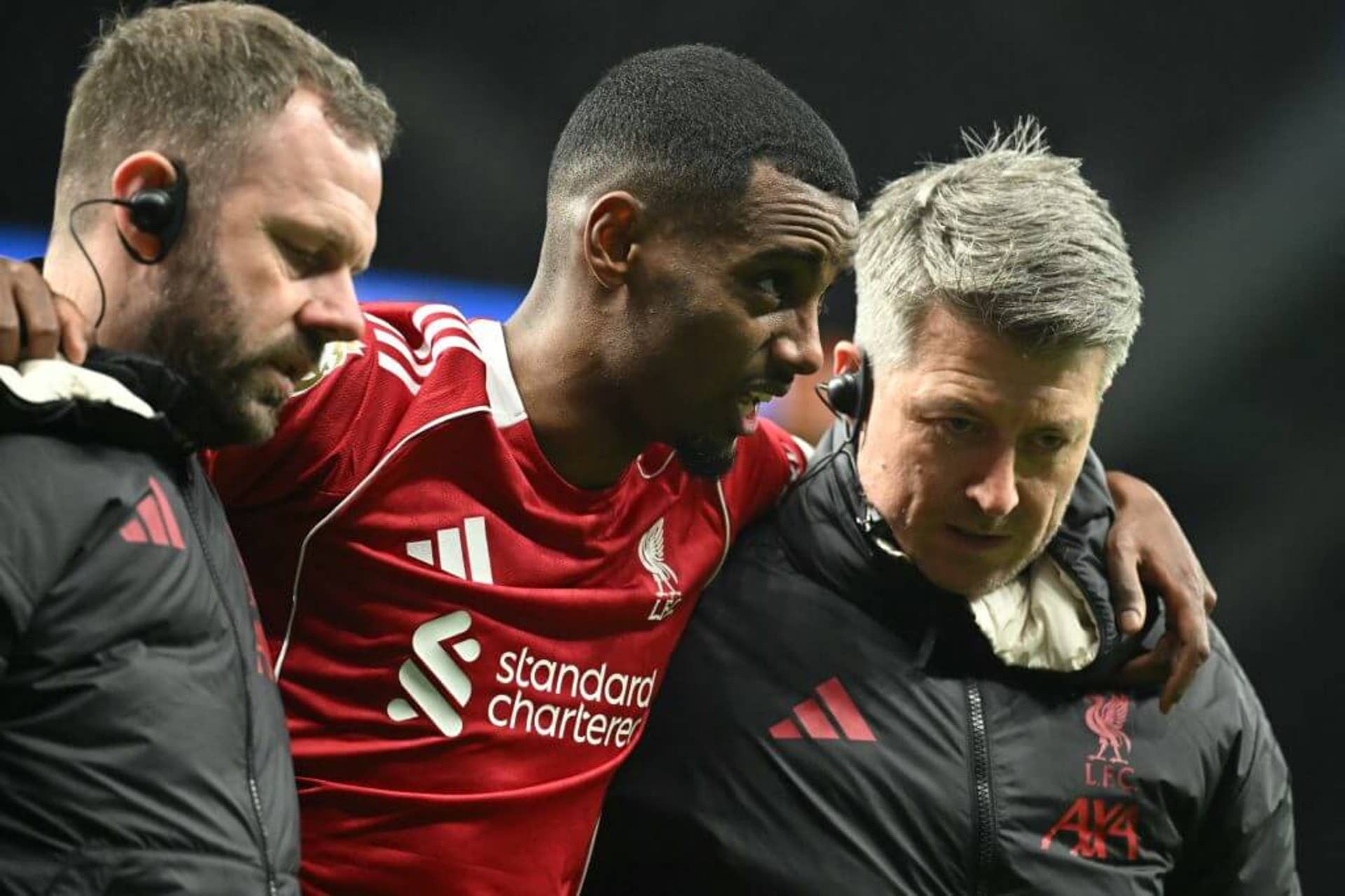 Close up of Isak being helped off the Tottenham Hotspur pitch by two members of Liverpool's medical team after his injury.