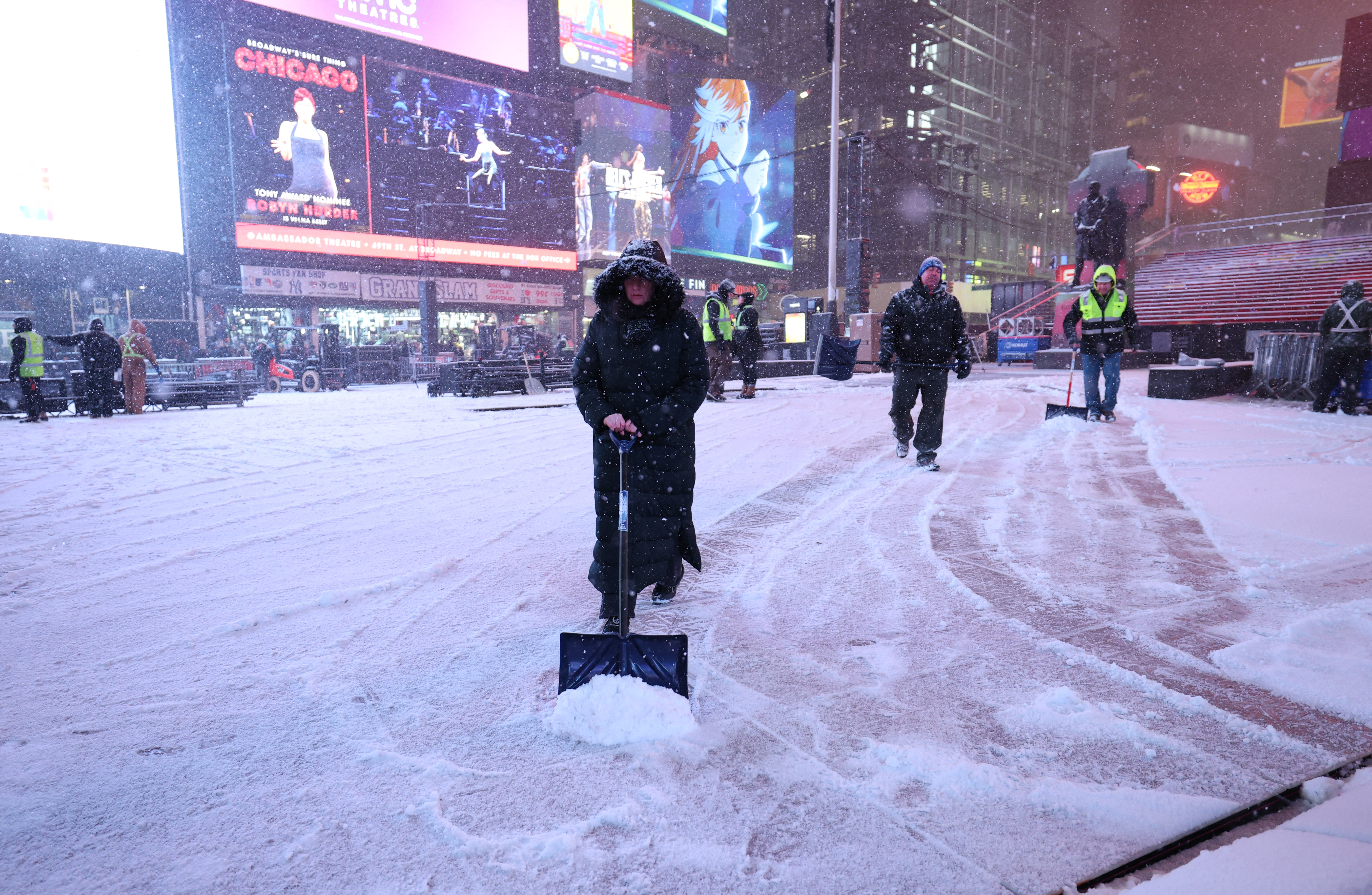 Workers clear away snow during a snowfall in Times Square...