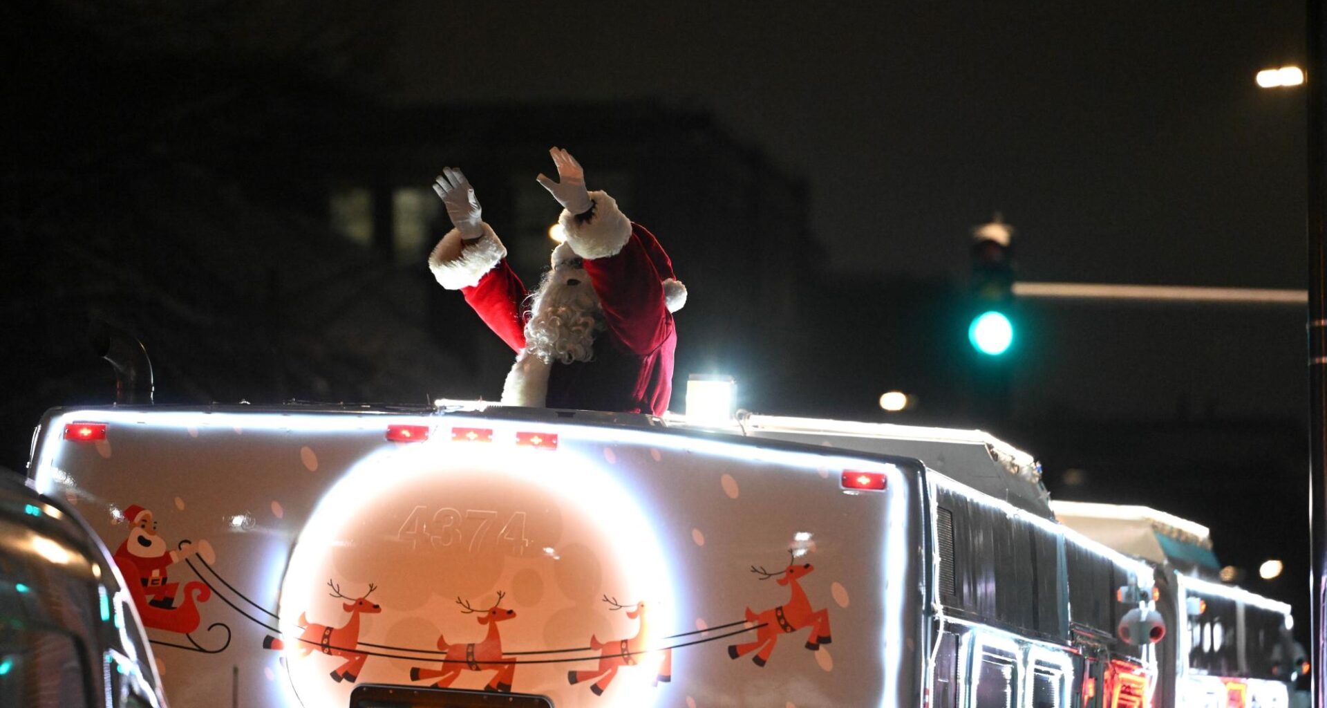 Santa waves from atop a city bus.
