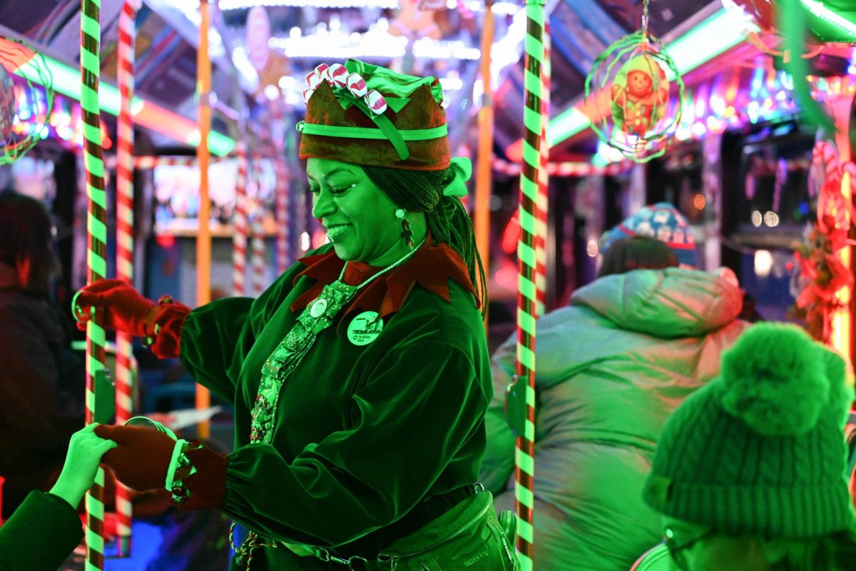 A woman in an elf costume holds a bus passenger’s hand.