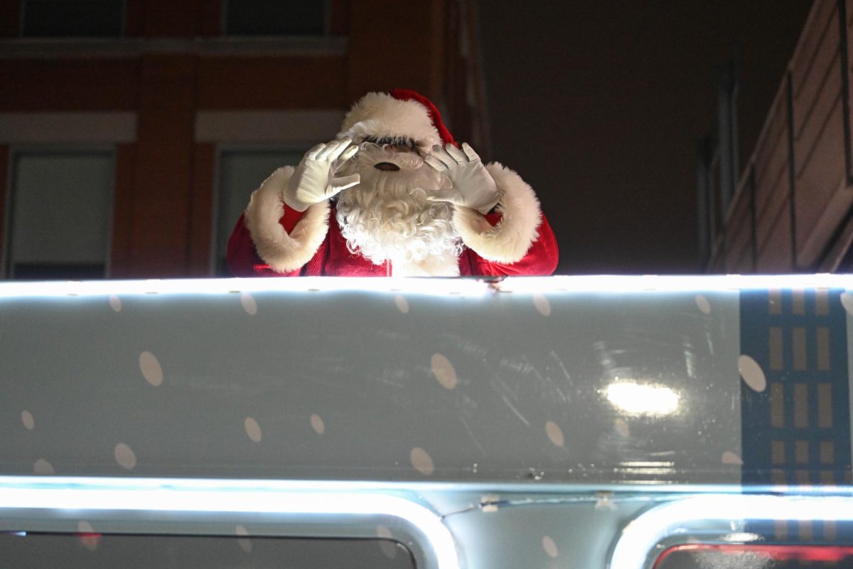 Santa waves from atop a city bus.