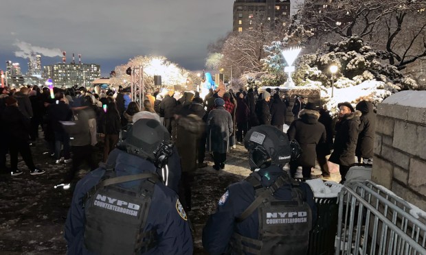 NYPD counterterrorism officers stand guard as people gather at Carl Schurz Park in Manhattan on Sunday night for a vigil in remembrance of the 15 people murdered in the Bondi Beach terrorist attack.