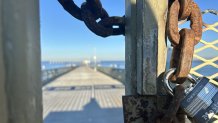 A rusted chain with a small lock is the only security holding the OB pier gates closed, December 7, 2025.