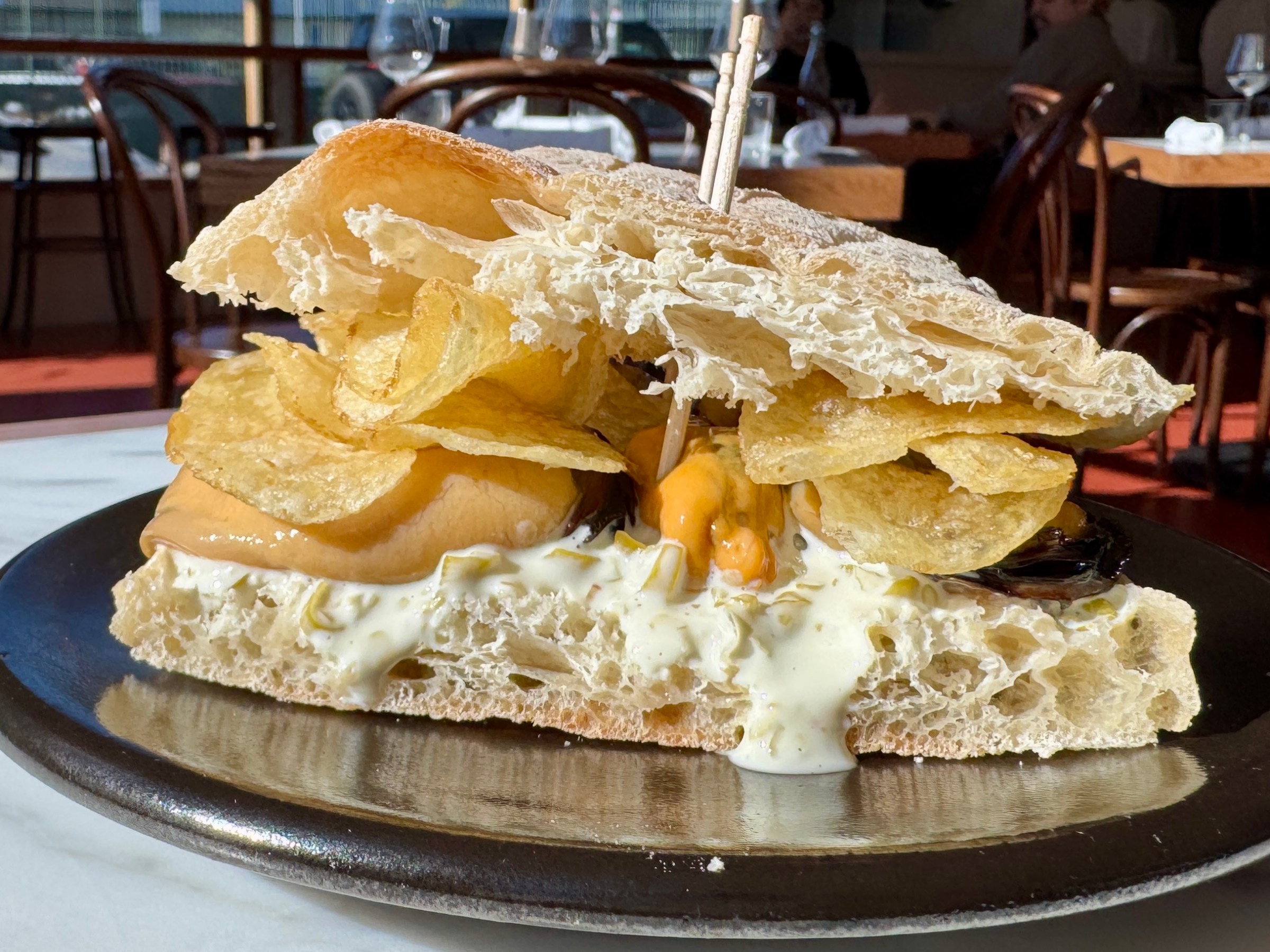 Cross section of a sandwich with mayonnaise, mussels, and potato chips at Little Fish Melrose Hill