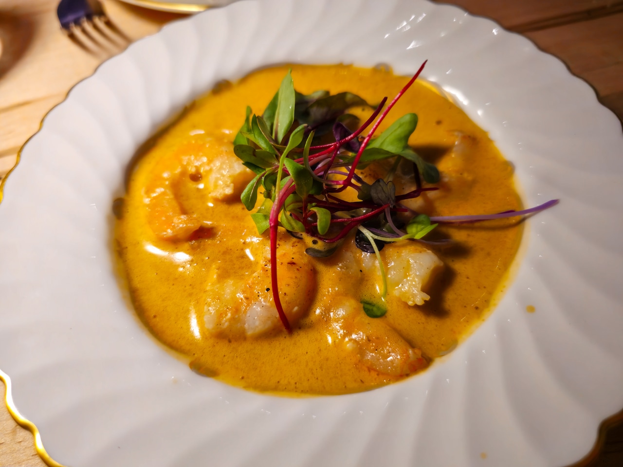 A bowl of shrimp and grits, garnished with pea shoots.