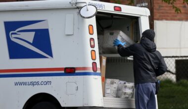 A U.S. Postal Service worker stops at a collection box on Secane Drive in Northeast Philadelphia in April 2020.