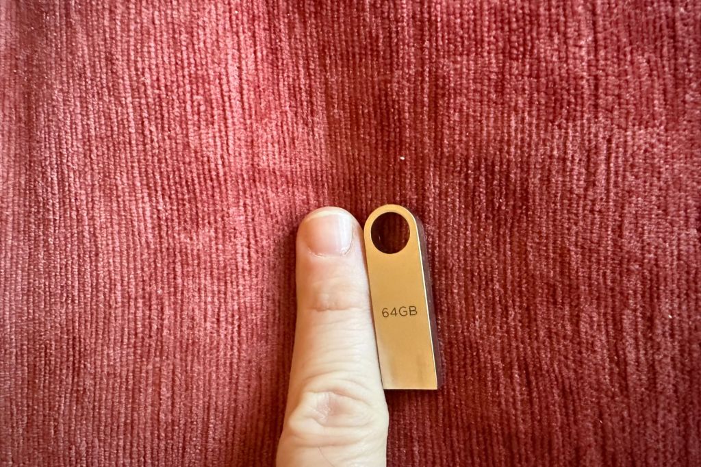 A human thumb next to a 64GB USB drive.