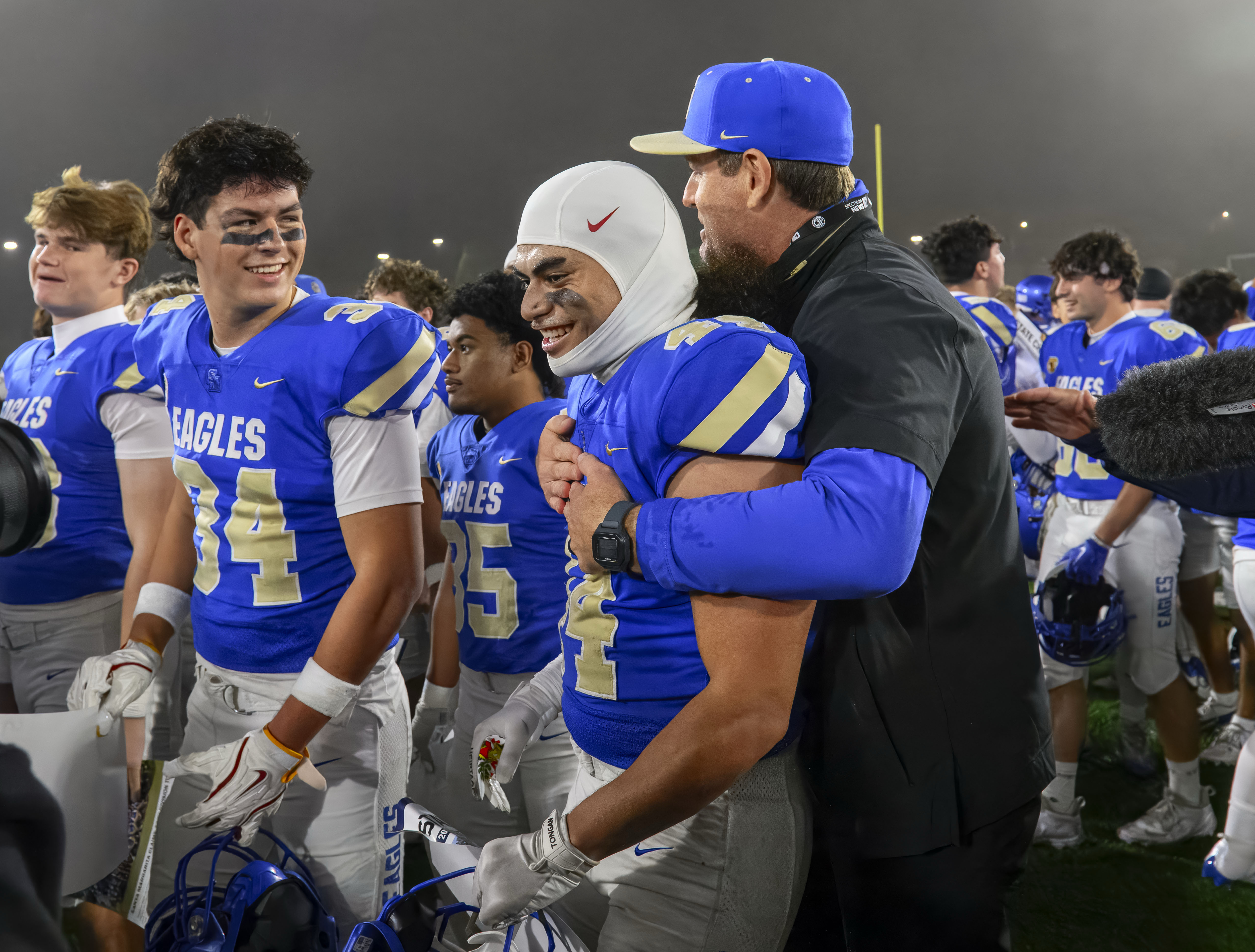 Santa Margarita middle linebacker Leki Holani is embraced by coach...