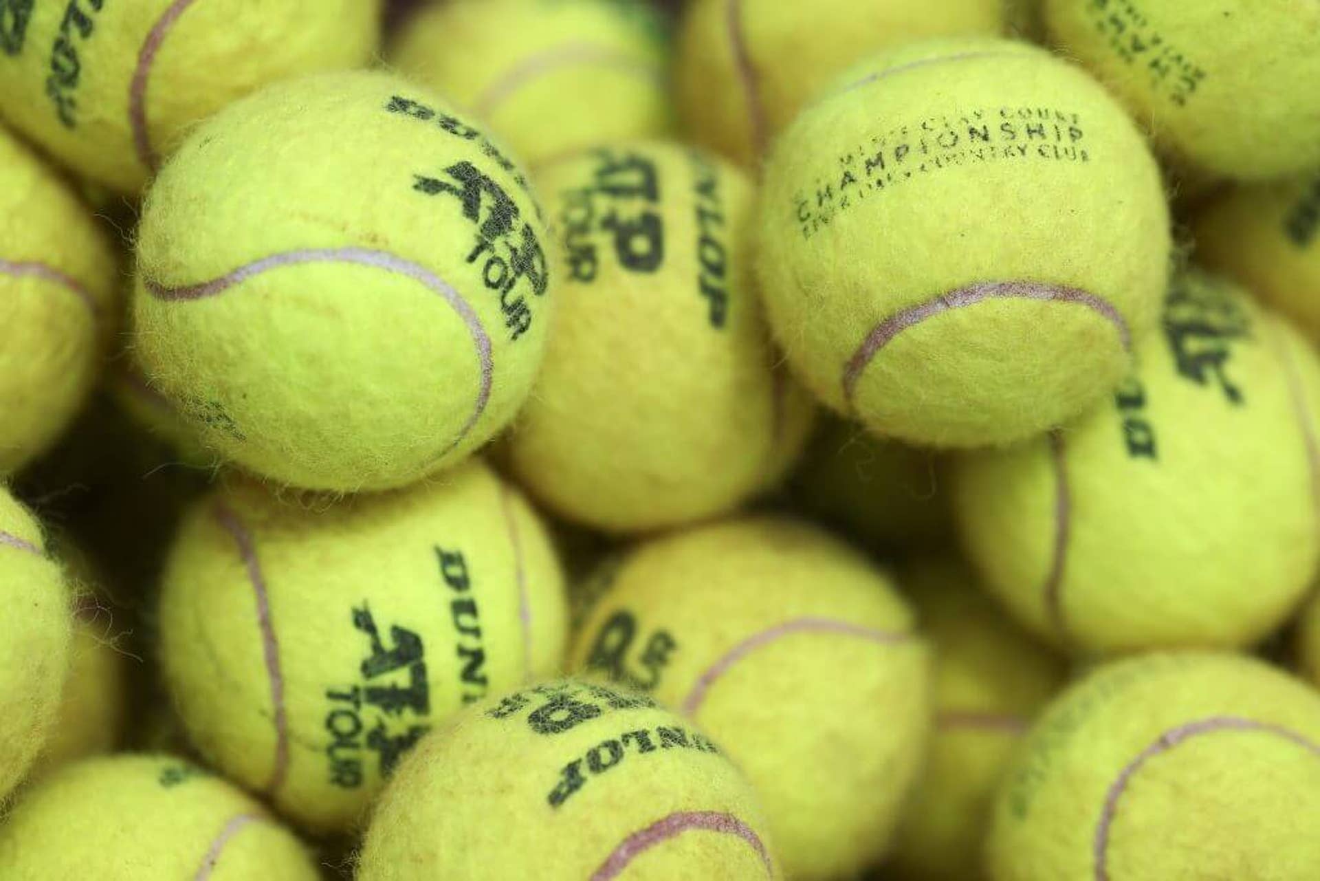 A collection of used tennis balls with the ATP Tour logo on them.