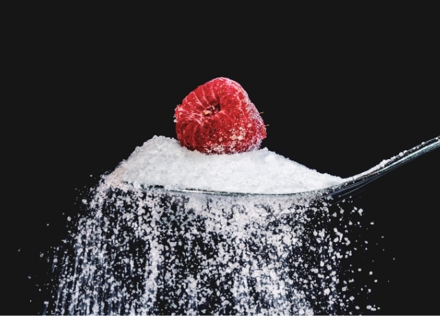 A spoonful of white sugar with a raspberry on top