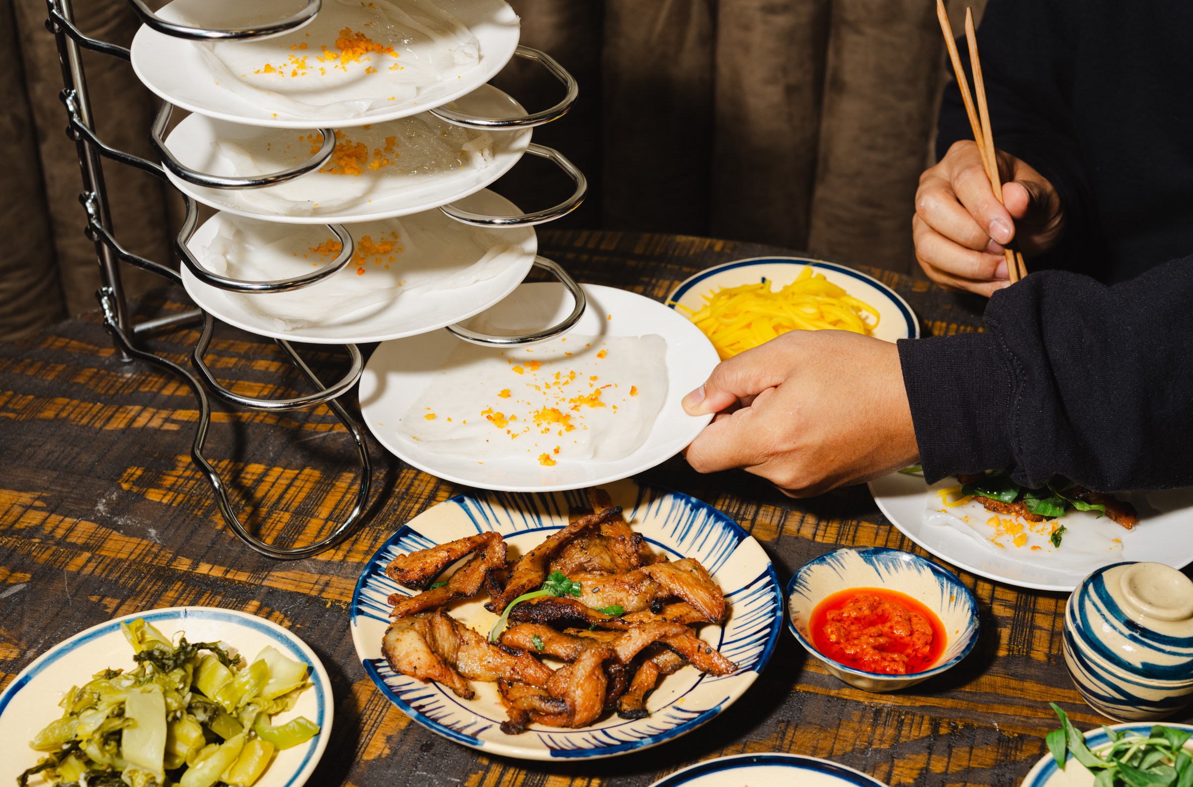A tower of rice sheets, surrounded by other small dishes to roll up in them.