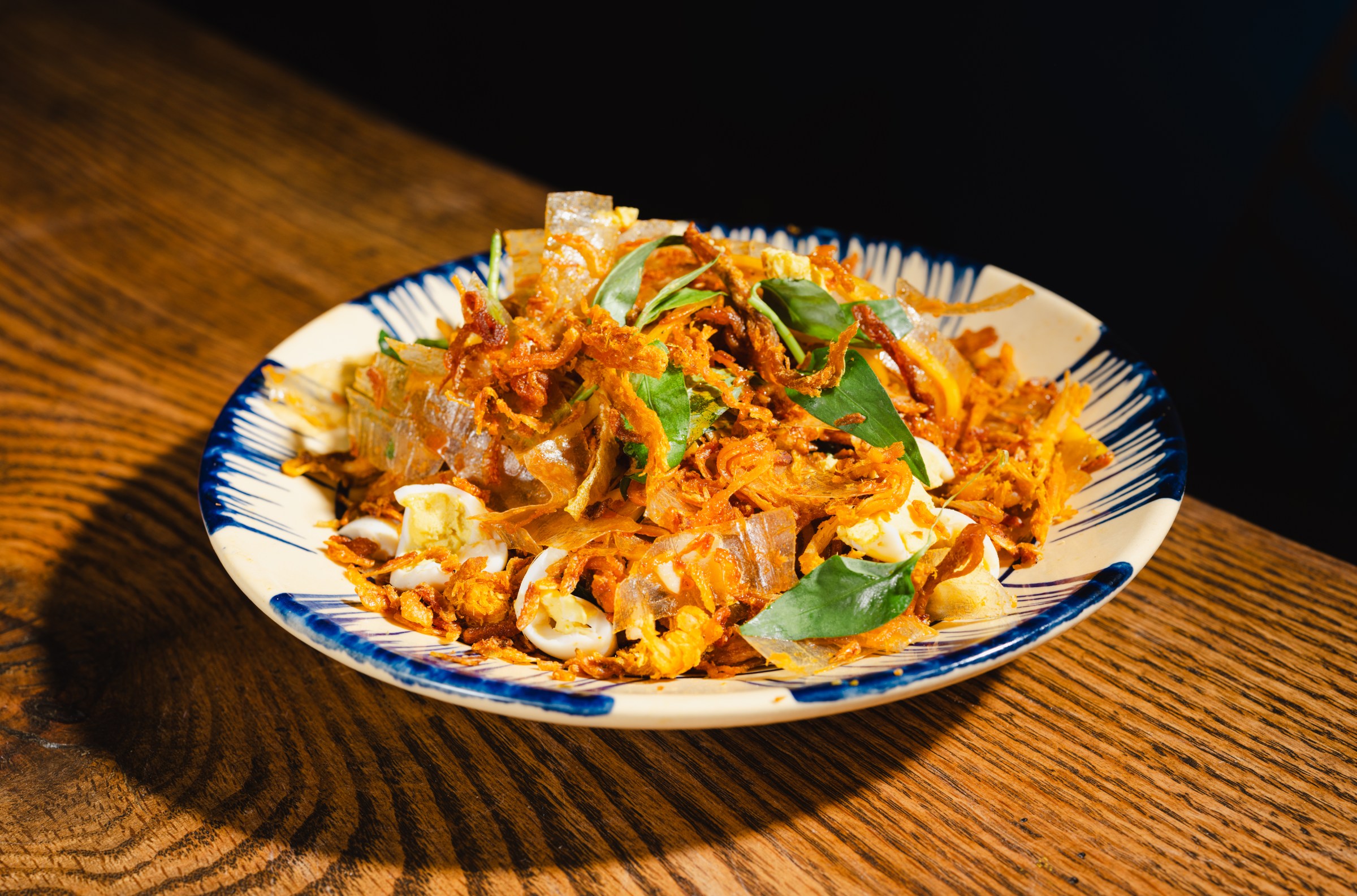 Crispy aromatics on top of a blue and white plate.