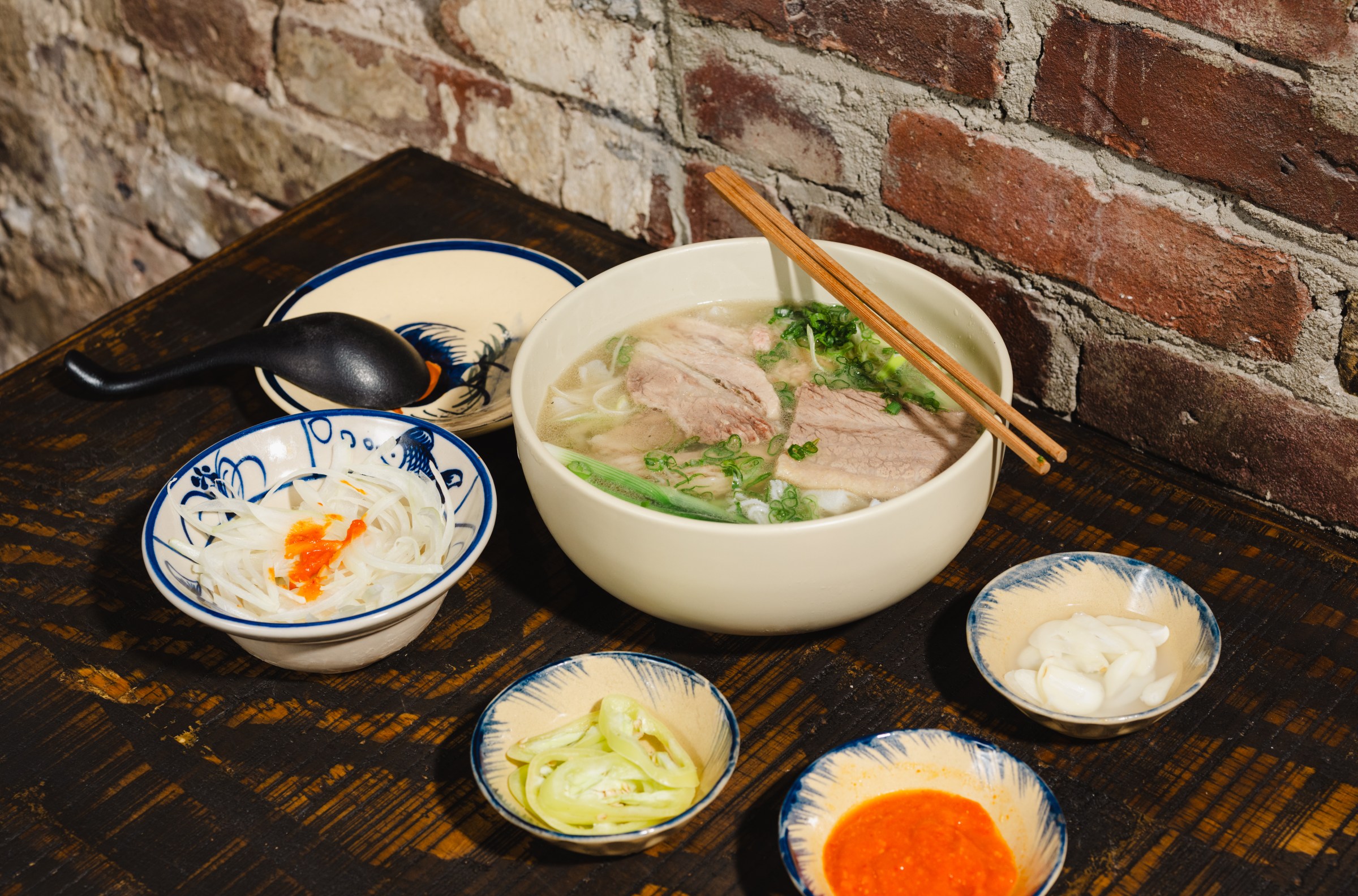 A bowl of soup with chopsticks surrounded by smaller bowls.