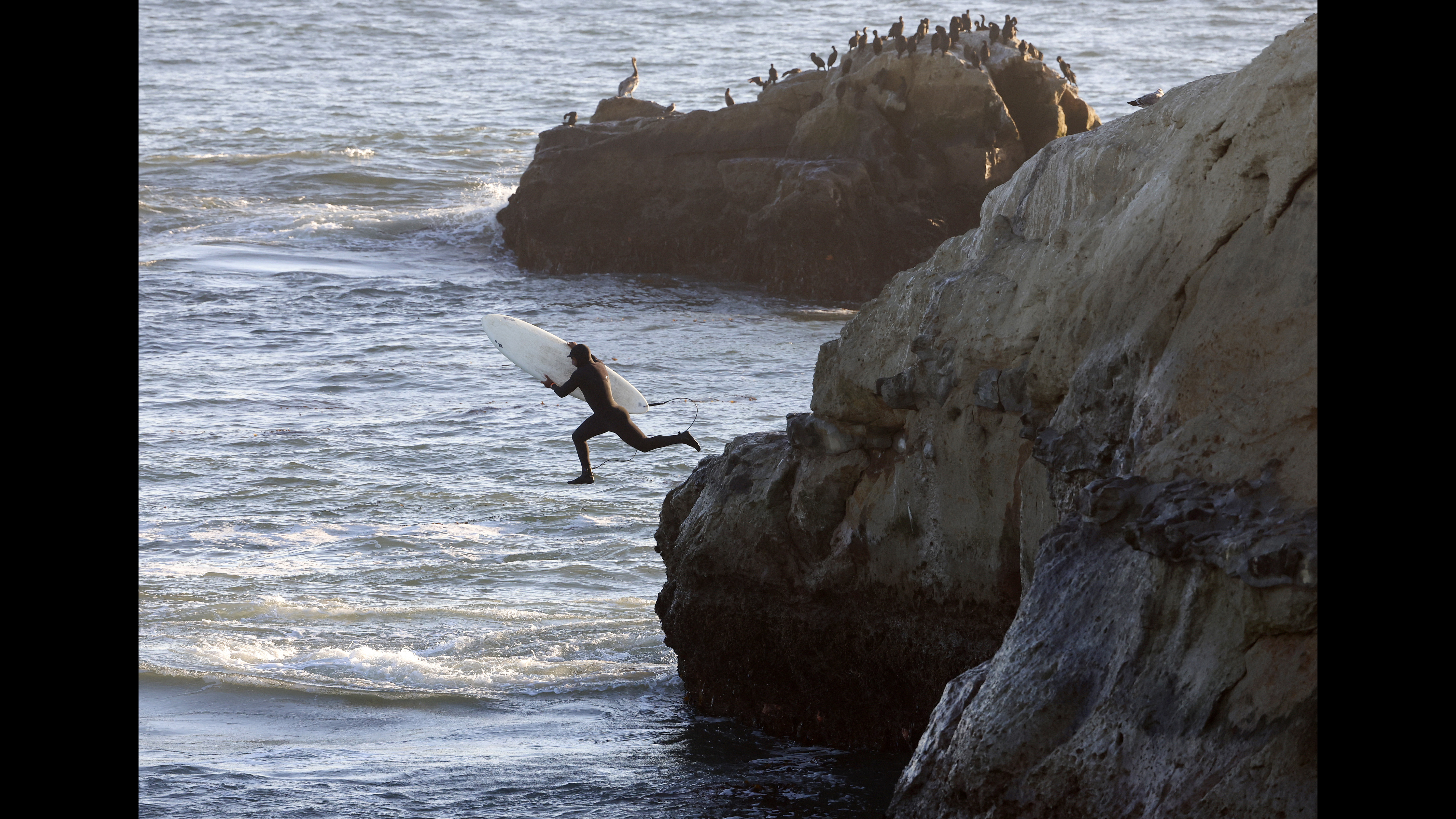 Ricardo Urbina of Aptos heads into the water with the...