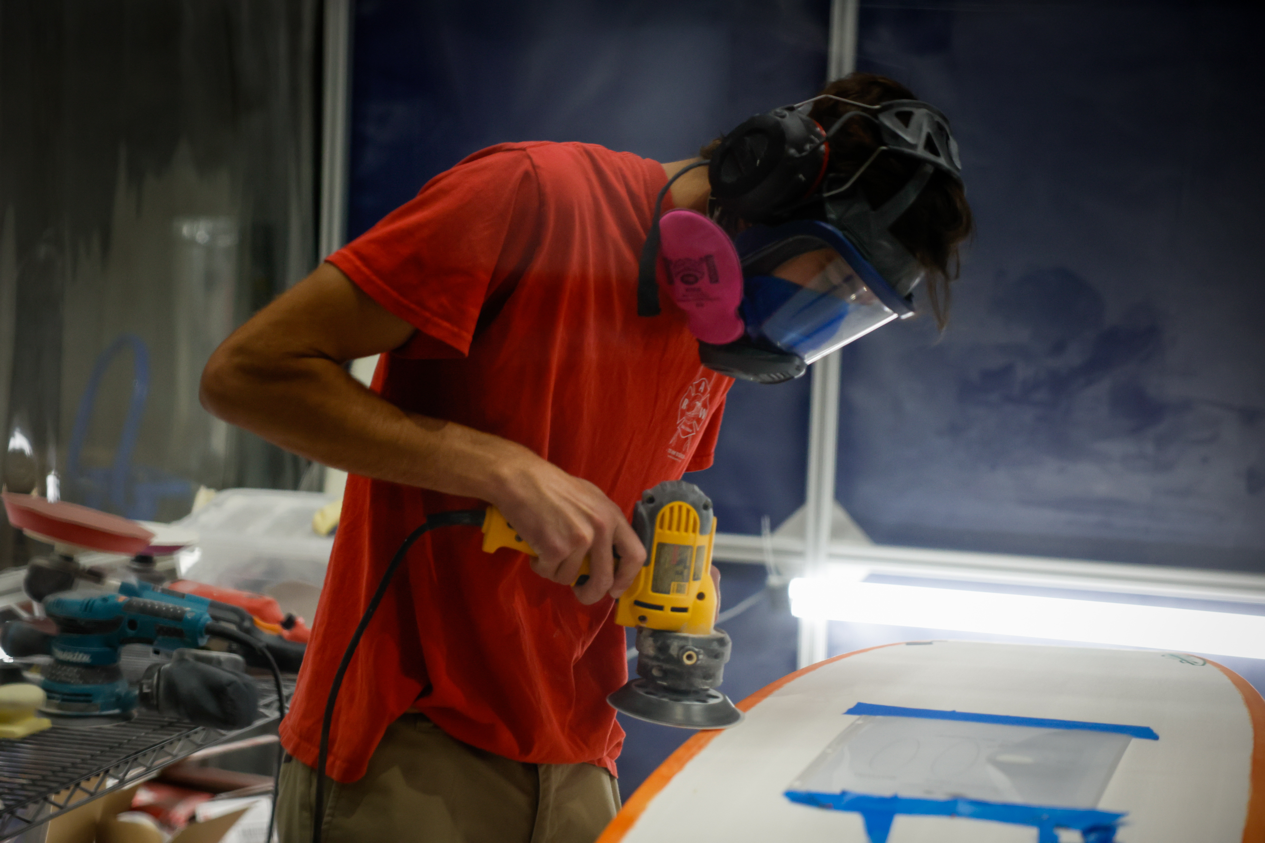 Quinn Comer, composite engineer, works on a surfboard at the...