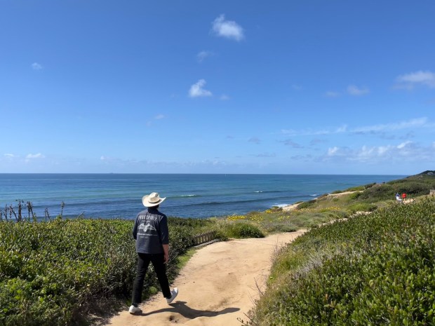 A hiker walks along the Coastal Trail, heading north.