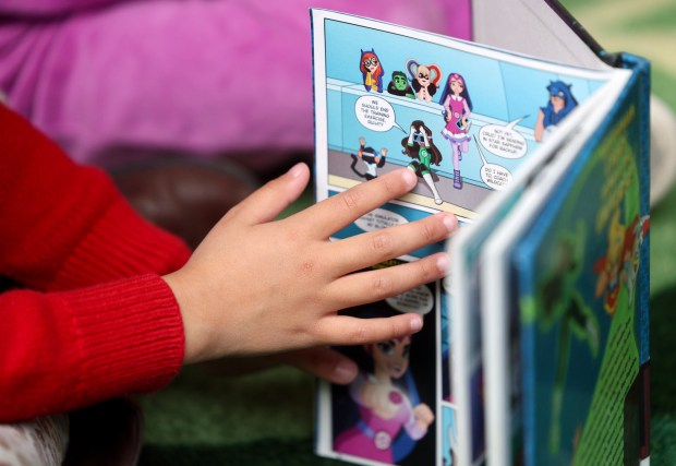 A young girl looks at a book at the Children's Library at the San Diego Central Library on Saturday, Dec. 20, 2025. (Hayne Palmour IV / For The San Diego Union-Tribune)