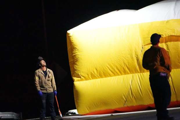 Firefighters set up a rescue air cushion as a man threatens to jump from the Del Mar Heights Road bridge to I-5 Friday. (Michael Ho / For The San Diego Union-Tribune)