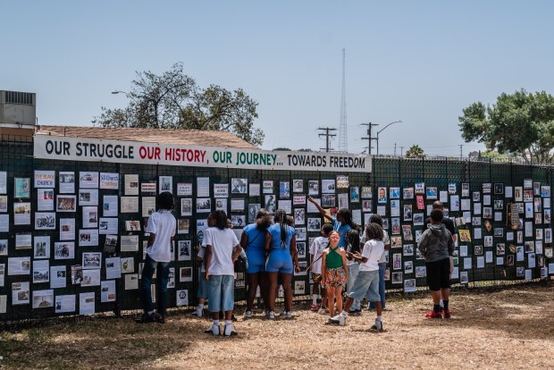 Kids stand in front of the "History Wall" during the Juneteenth celebration, hosted by the Cooper Family Foundation in Logan Heights on June 21, 2025. (Ariana Drehsler / For The San Diego Union-Tribune)