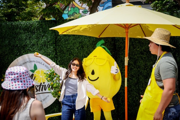 Attendees take Selfie photos along 3rd Avenue during the Chula Vista Lemon Festival in Chula Vista on Saturday, Aug. 16, 2025. This year's Lemon Festival features food and drinks, two stages of live music, a lemon cook-off competition, arts and crafts vendors and several photo op spots. (Sandy Huffaker / For The San Diego Union-Tribune)