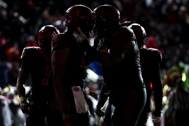 San Diego State quarterback Jayden Denegal (4) and center Ross Ulugalu-Maseuli (63) celebrate after a touchdown against the Boise State Broncos during their game at Snapdragon Stadium on Saturday, Nov. 15, 2025 in San Diego, California. (Meg McLaughlin / The San Diego Union-Tribune)