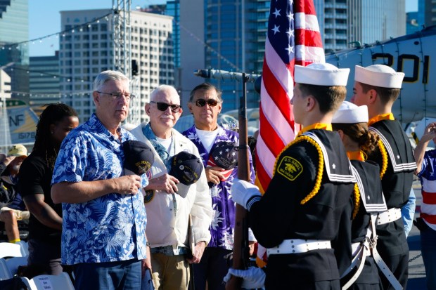 During the 84th Annual Pearl Harbor Remembrance Day Ceremony on board the USS Midway, Dennis Fipps (l), Ben Valeu (m), and David Ybarra (r) stood during the presenting of the colors and playing of the national anthem... (Nelvin C. Cepeda / The San Diego Union-Tribune)
