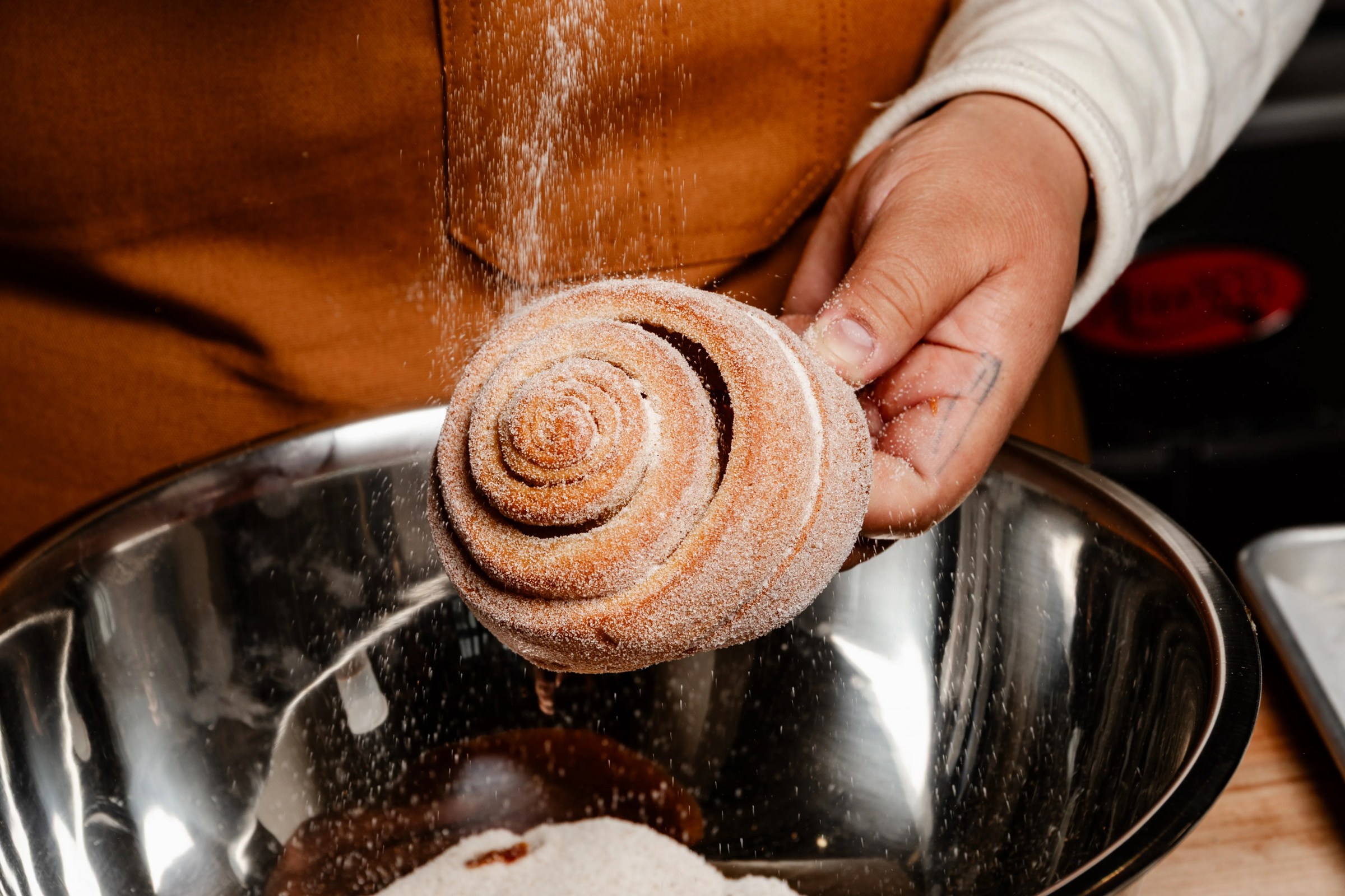 Ellen Ramos dusting a pastry with cinnamon sugar at Santa Canela.