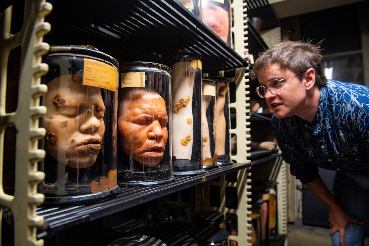 Sara Ray, Senior Director of Interpretation and Engagement at the Mutter Museum Historical Medical Library, examines wax models of the faces of patients who suffered from leprosy, in the stacks of the museum's archives.