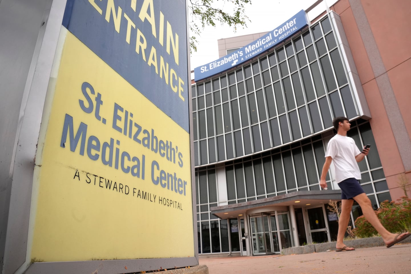 A passer-by walks past an entrance to St. Elizabeth's Medical Center, now called BMC Brighton, on Thursday, Sept. 19, 2024, in the Brighton neighborhood of Boston.  (AP Photo/Steven Senne)