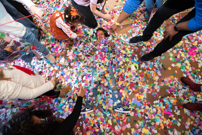 Saigen Cuffee, 2, helps to bury her brother Huxon Cuffee, 4, under a mound of confetti as...