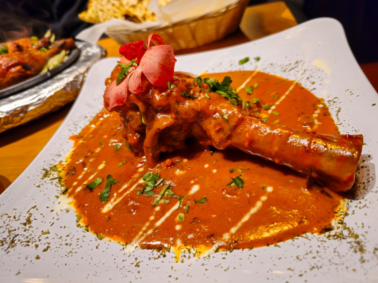 A stewed lamb shank in a red tikka masala sauce.