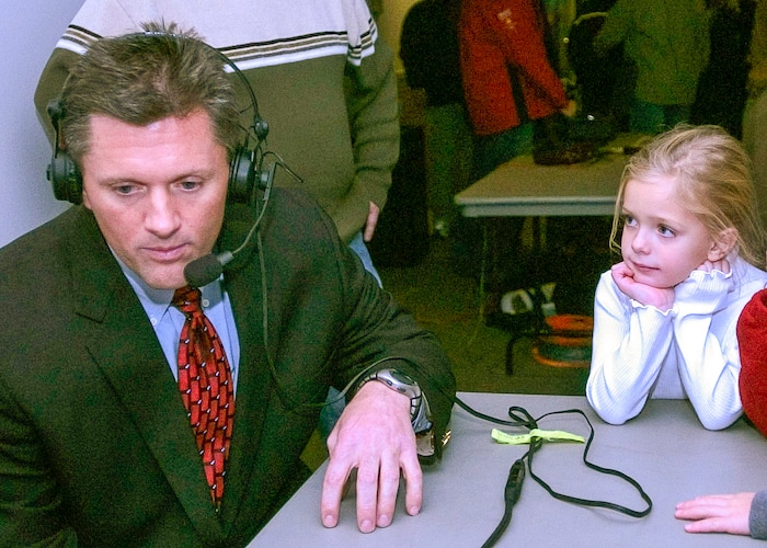 (Rick Egan | The Salt Lake Tribune) Kyle Whittingham answers questions on the radio as his 6-year-old daughter Kylie watches after Whittingham was announced as the next head football coach in December 2004.