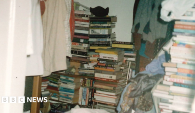 The bedroom of a person with hoarding disorder, stacked high with piles of books and clothes.