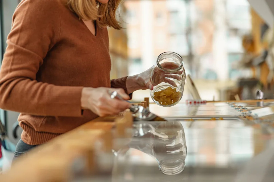 Person refills a glass jar with dried pasta in a sustainable, plastic-free store