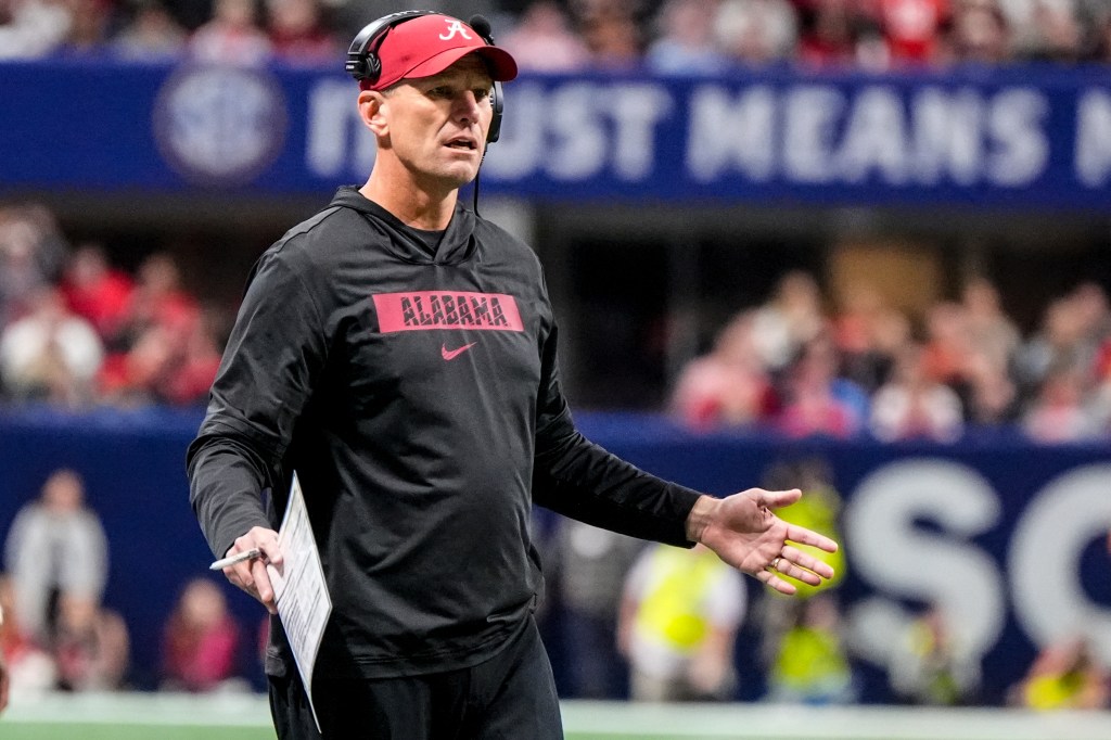 Alabama head coach Kalen DeBoer speaks to an official during an SEC Championship college football game.