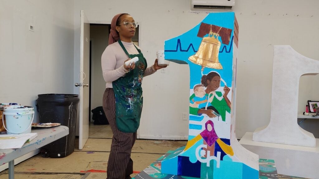 Aaminah Rasheed paints on number 1 sculpture
