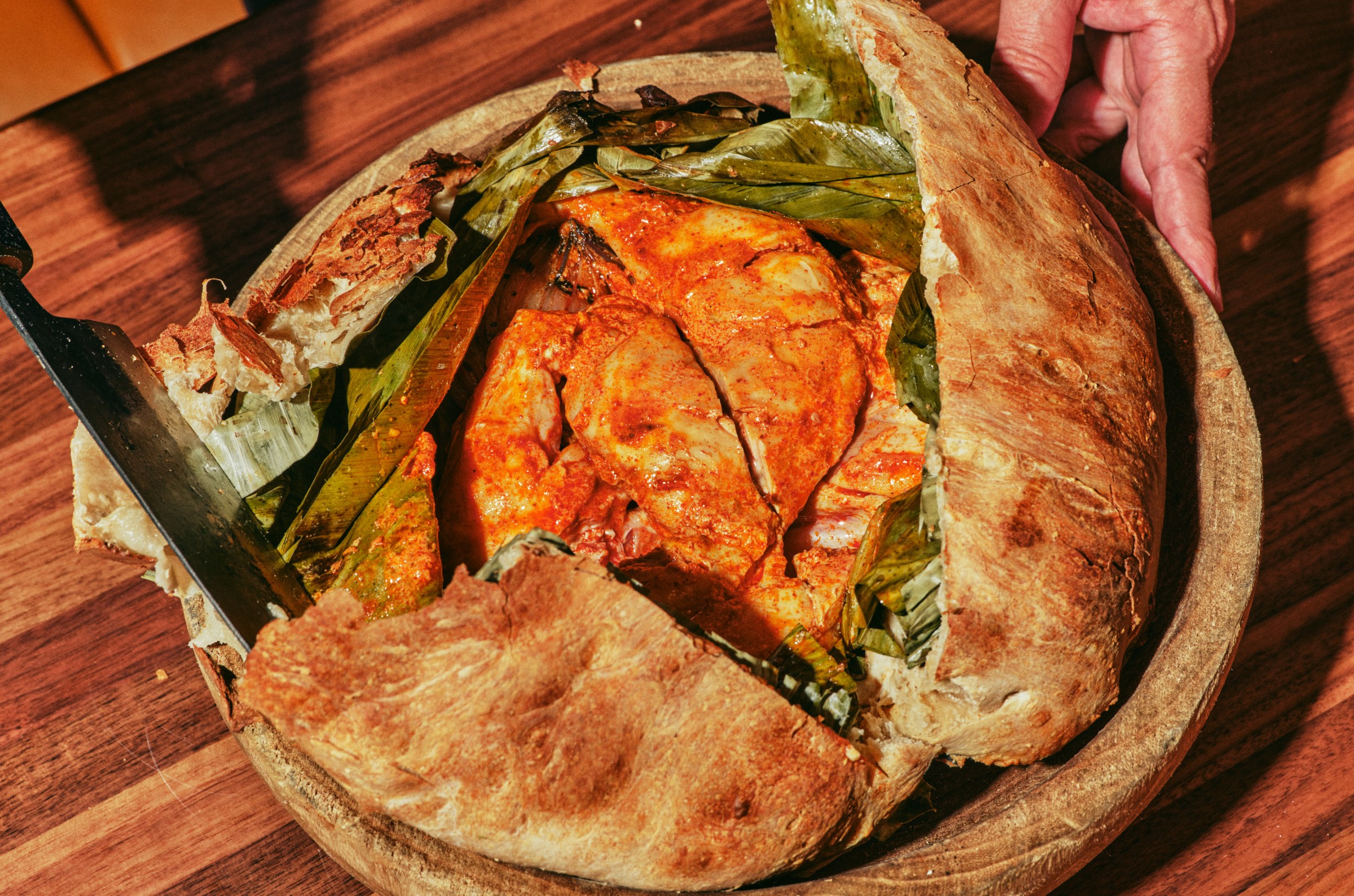 A roasted chicken in a pan covered in bread.