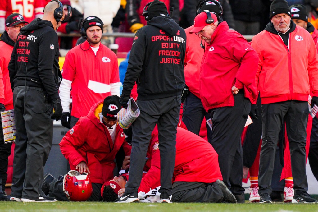 Medical staff attending to Kansas City Chiefs quarterback Patrick Mahomes on the field with coach Andy Reid observing.