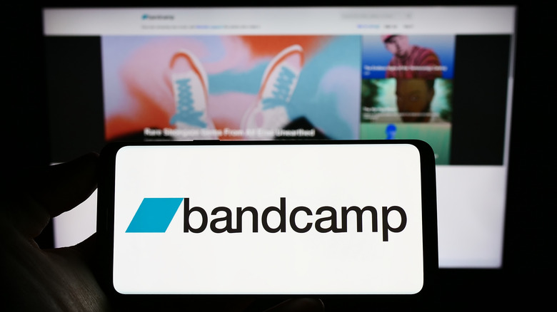 Bandcamp logo on a smartphone placed in front of a big screen