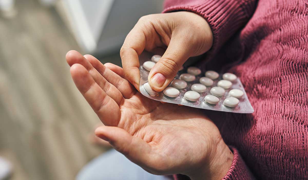 Close perspective of hands carefully holding a blister pack with white pills, emphasizing health and medication concepts.