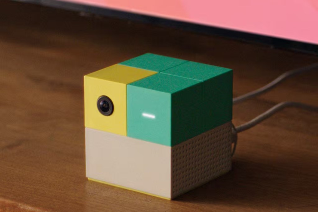 Modular camera with a yellow lens component, two green components, and a light tan component, with wires emerging from its side.