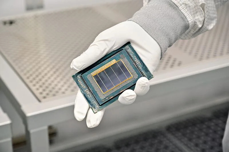 An Intel manufacturing technician holds a Clearwater Forest chip inside the cleanroom of Intel’s new Fab 52 in Chandler, Arizona, in September 2025. Fab 52 is the U.S. home to Intel 18A, where Clearwater Forest, a data center processor, will be manufactured. | Intel via Business Wire