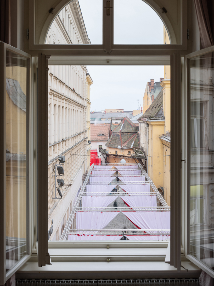 red and white curtains transform czech historic center’s pathways into christmas installation