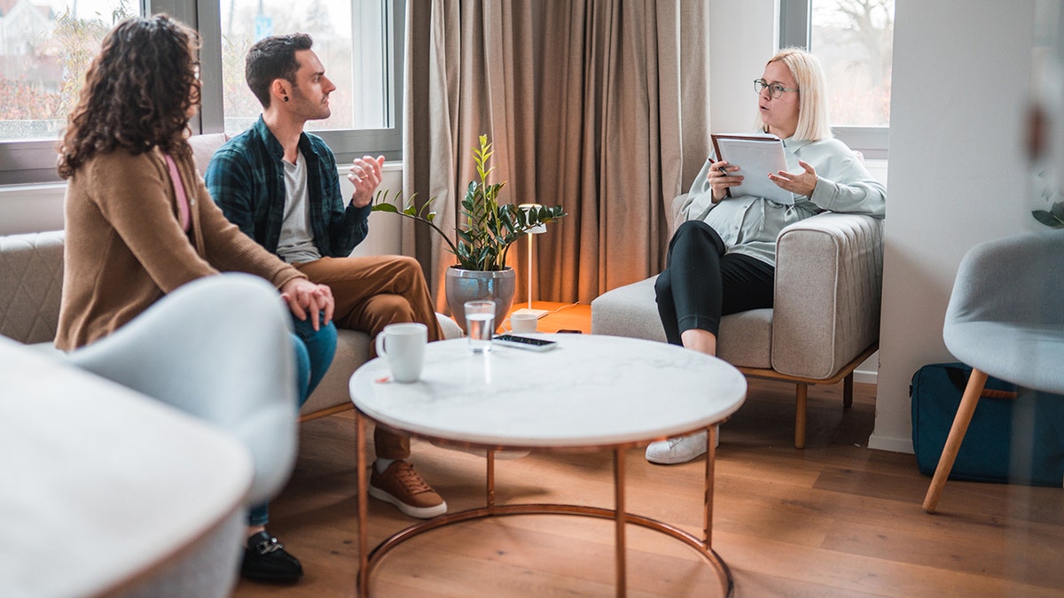 Couple talking to female therapist on couch in her office.
