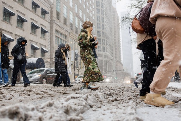 People walk through the snow along North Michigan Avenue as a winter storm passes through the area on Nov. 29, 2025, in Chicago. (Armando L. Sanchez/Chicago Tribune)