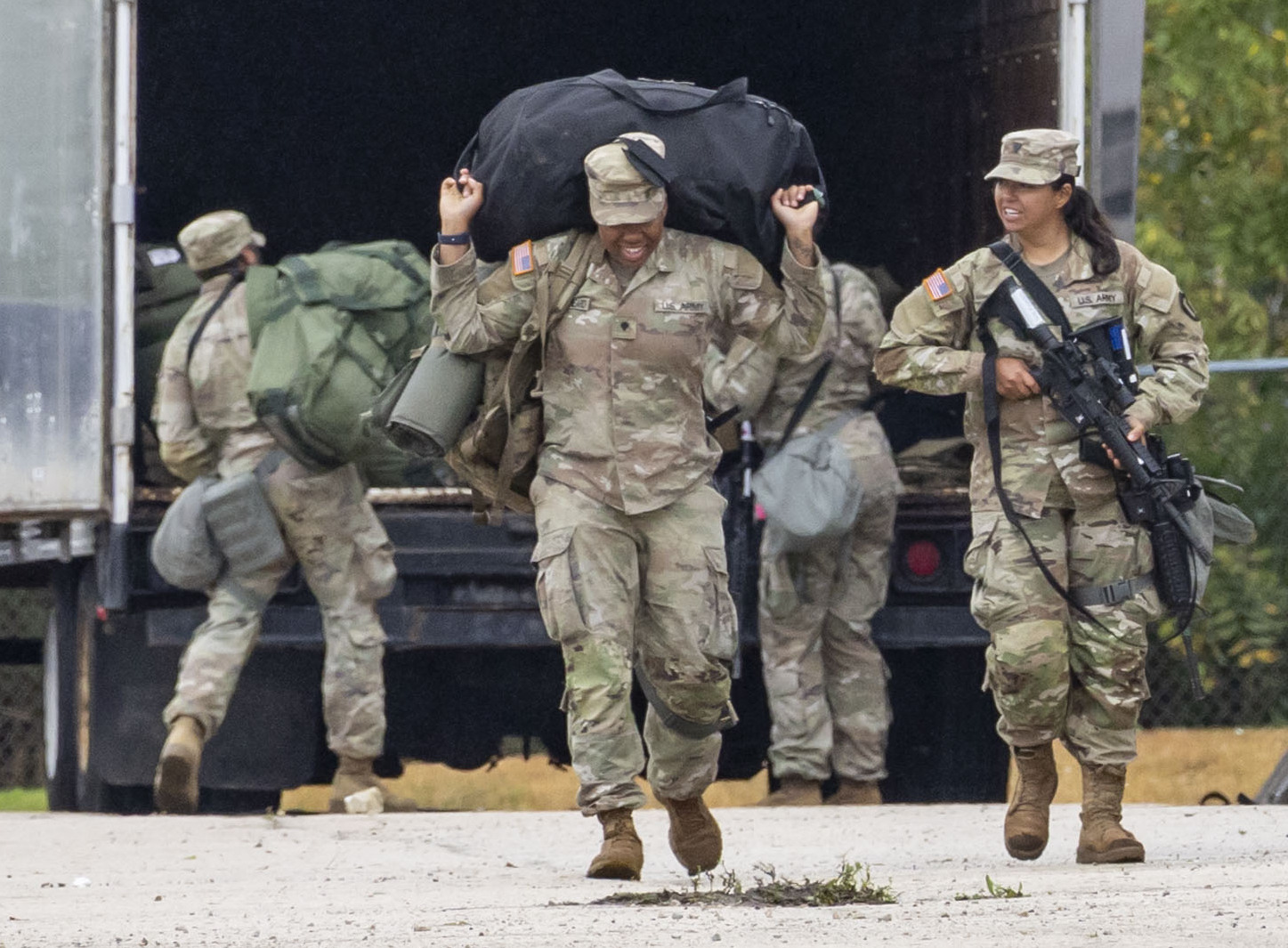 Members of the Texas National Guard carry luggage after arriving...