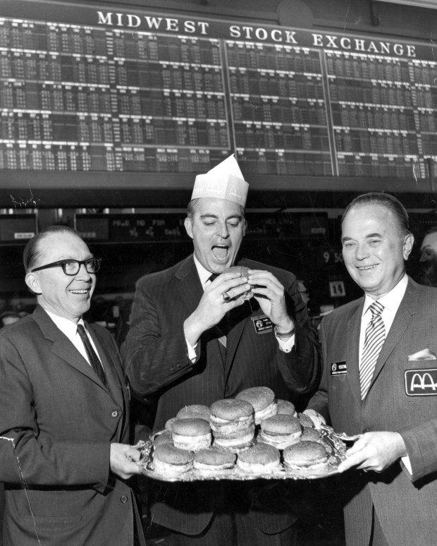 Frank J. Rothing, center, senior vice president of the Midwest Stock Exchange (MSE), samples one of the 3.5 million hamburgers a day McDonald's Corporation serves at its more than 1,200 outlets, in honor of the listing of the Chicago-based restaurant chain's common stock on the MSE. With Rothing are Robert C. Wilson Jr., left, MSE specialist for the stock, and Ray A. Kroc, chairman and founder of McDonald's. (Chicago Tribune archive) 