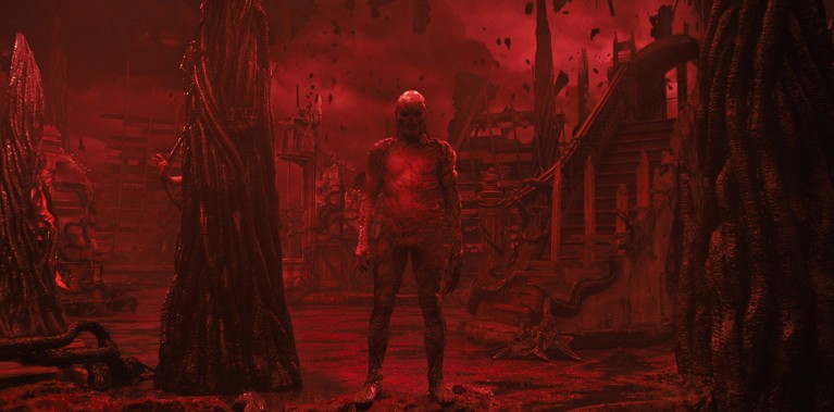 A still of Vecna standing in his otherworldly red tinted home in the "Upside Down" dimension from the Season 4 of the Stranger Things tv series.