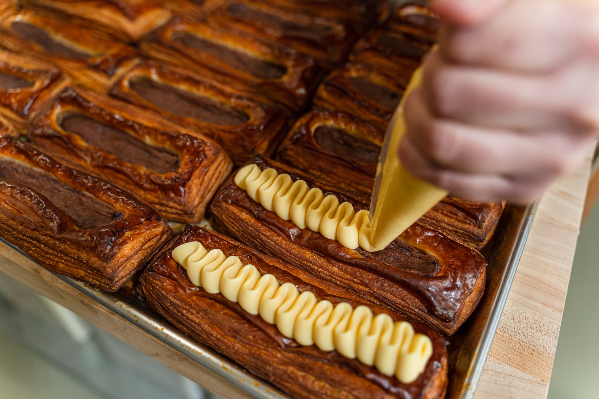 Pastries receive zigzags of yellow cream.