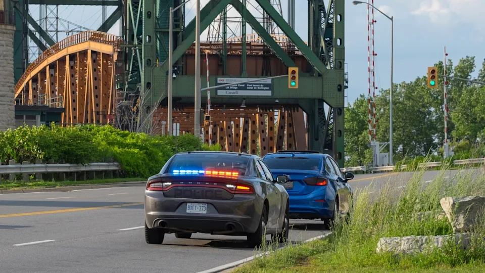An undercover unmarked police OPP vehicle with flashing red and blue lights has pulled over a car on the side of the road
